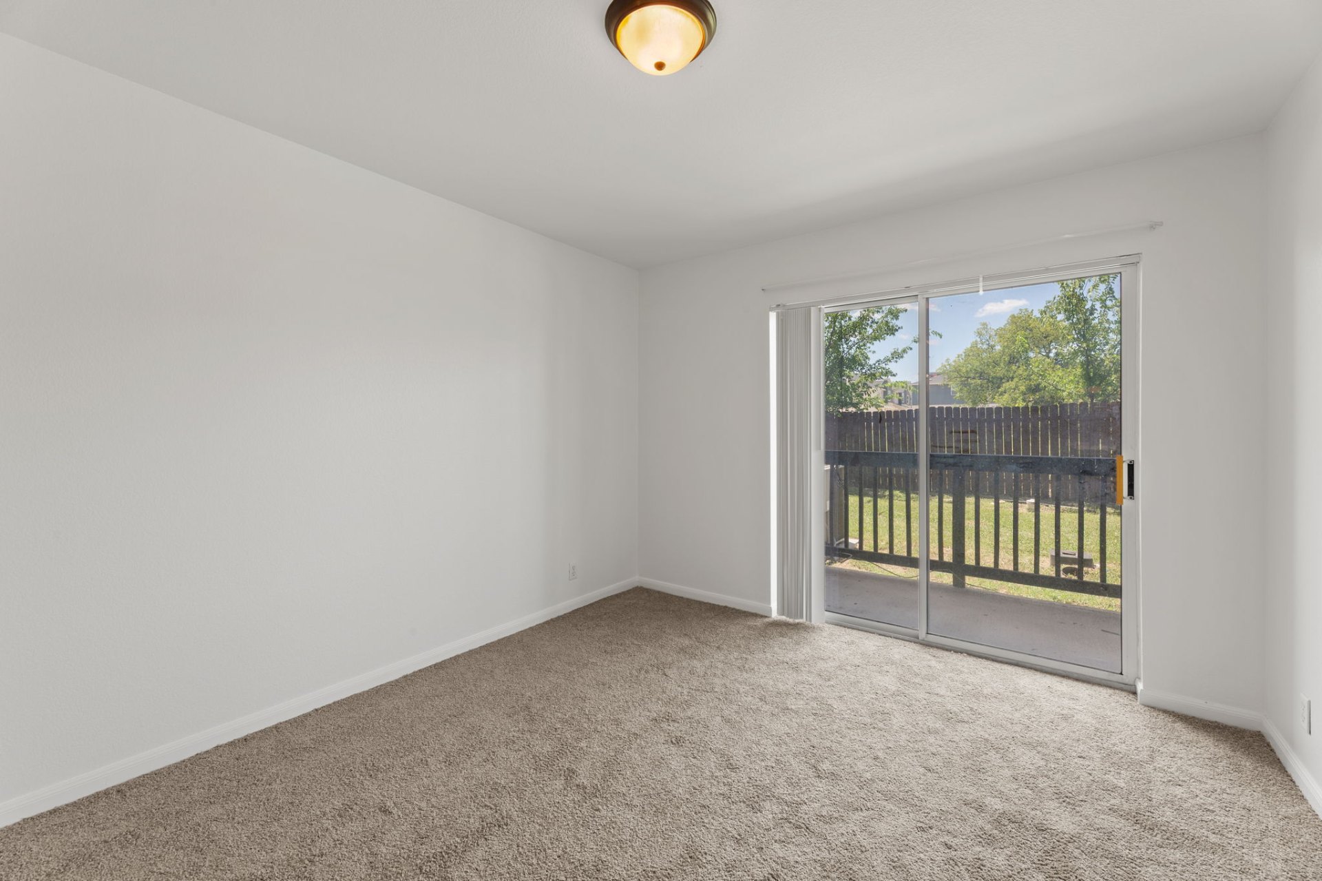Classic-finish bedroom with fresh carpet and sliding glass door to the yard