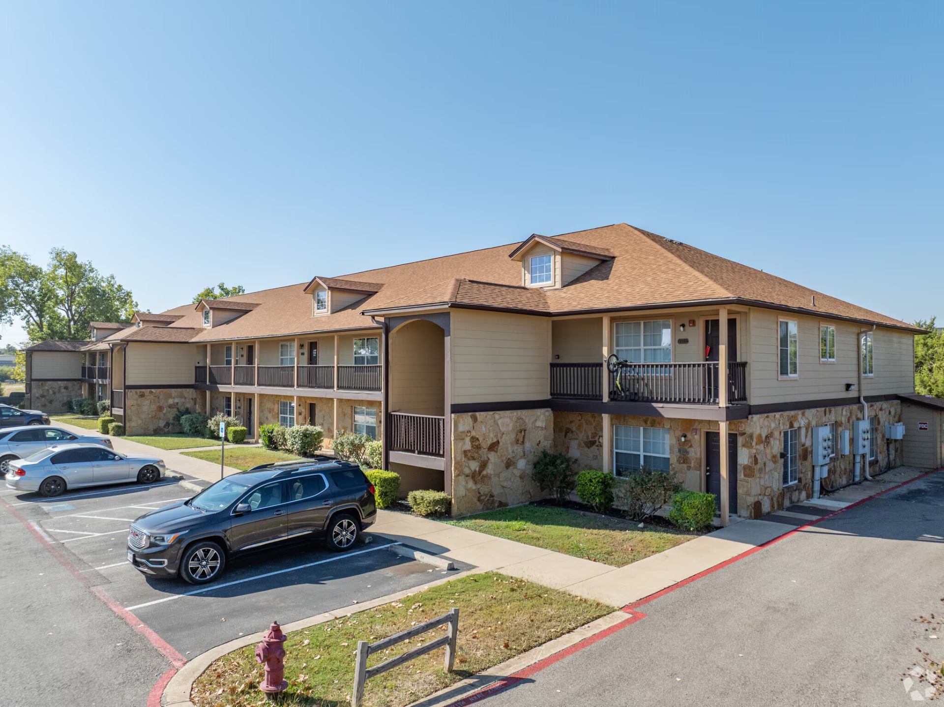 Corner of a Montierra Ranch building with stone base, upper balconies, and shaded parking